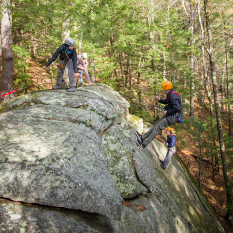 UNH学生在一块大岩石上攀爬